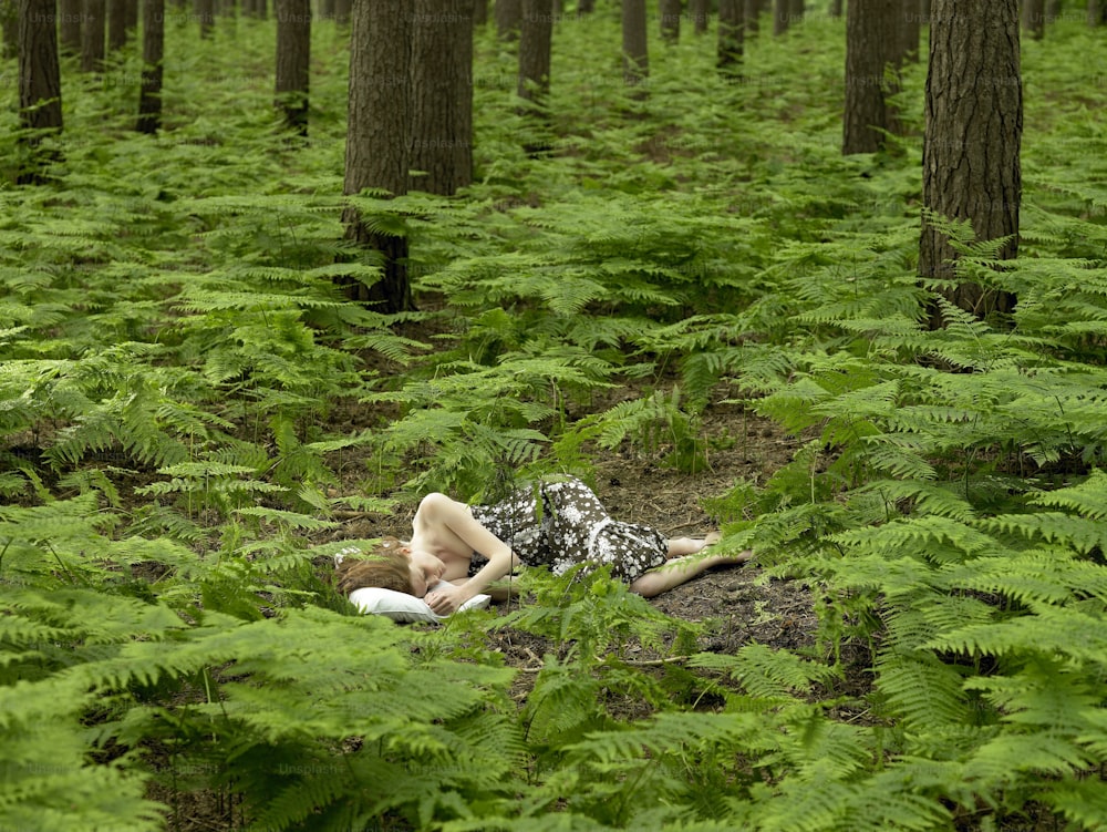 a woman laying on the ground in the middle of a forest
