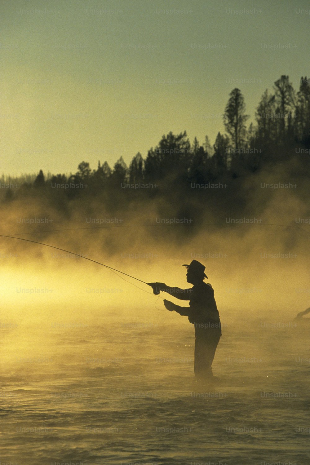 a man standing in the water while holding a fishing rod