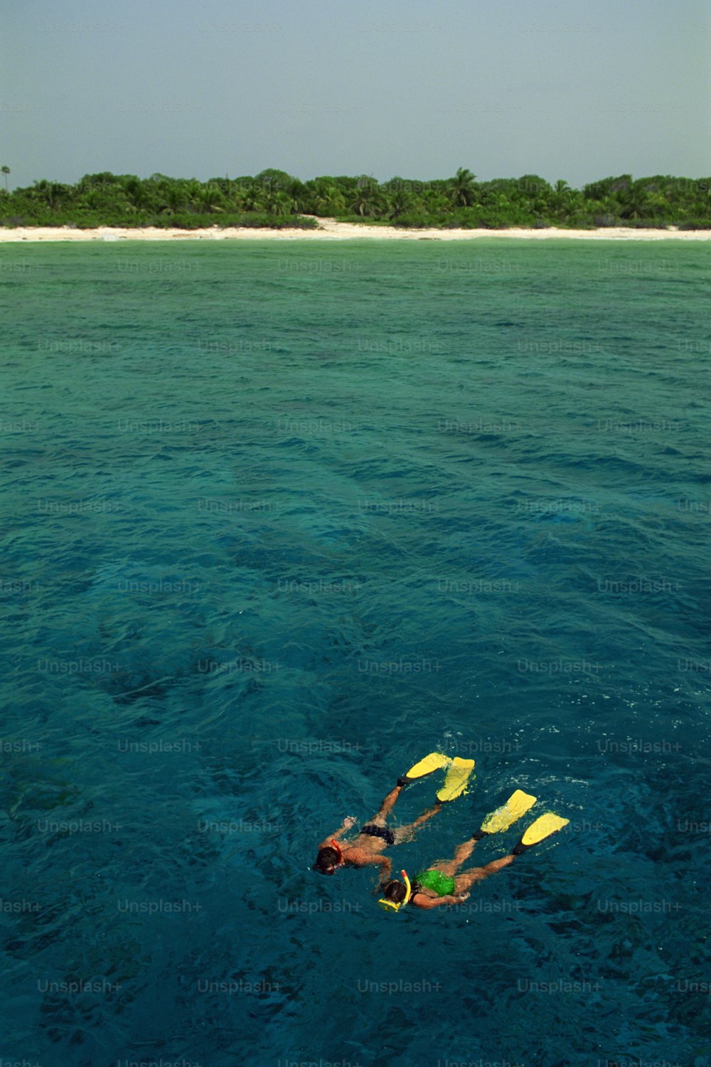 男が2つの黄色いカヤックで海を泳いでいる
