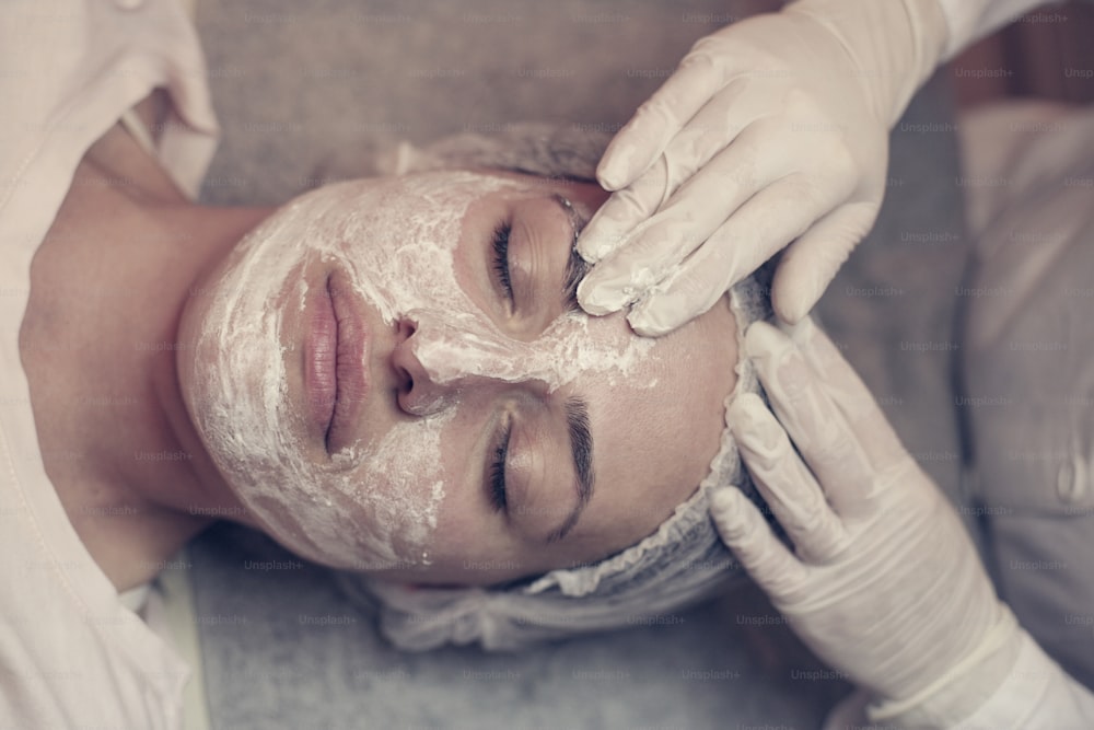 Giovane donna in un centro termale. Sdraiata su un lettino da massaggio con una maschera sul viso.