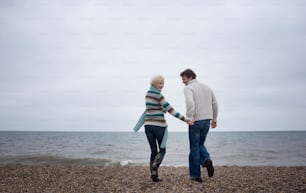 Un uomo e una donna che camminano su una spiaggia tenendosi per mano