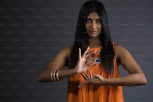 a woman in an orange dress making a peace sign