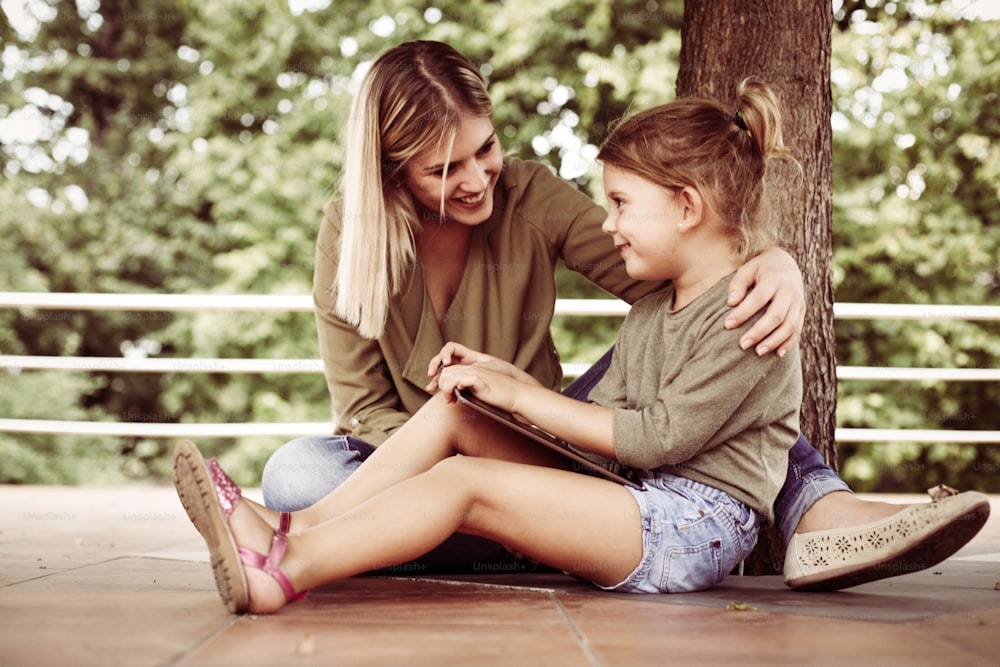 Mãe alegre com sua filha usando tablet.