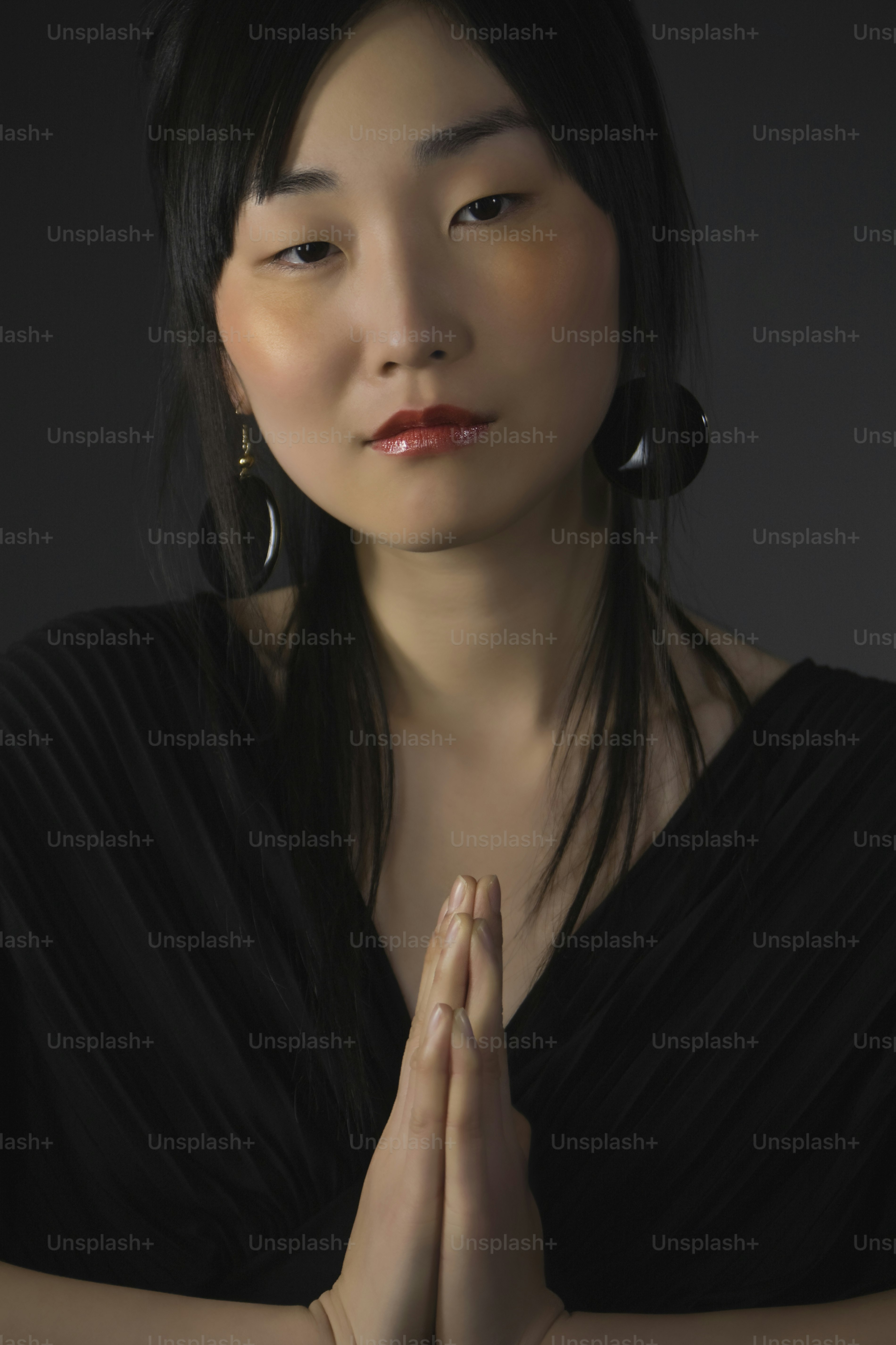 uma mulher com um vestido preto segurando as mãos juntas