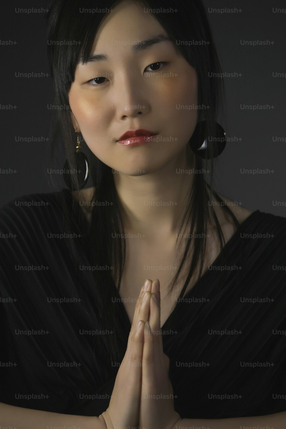 a woman in a black dress holding her hands together