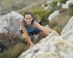 a woman climbing up the side of a large rock