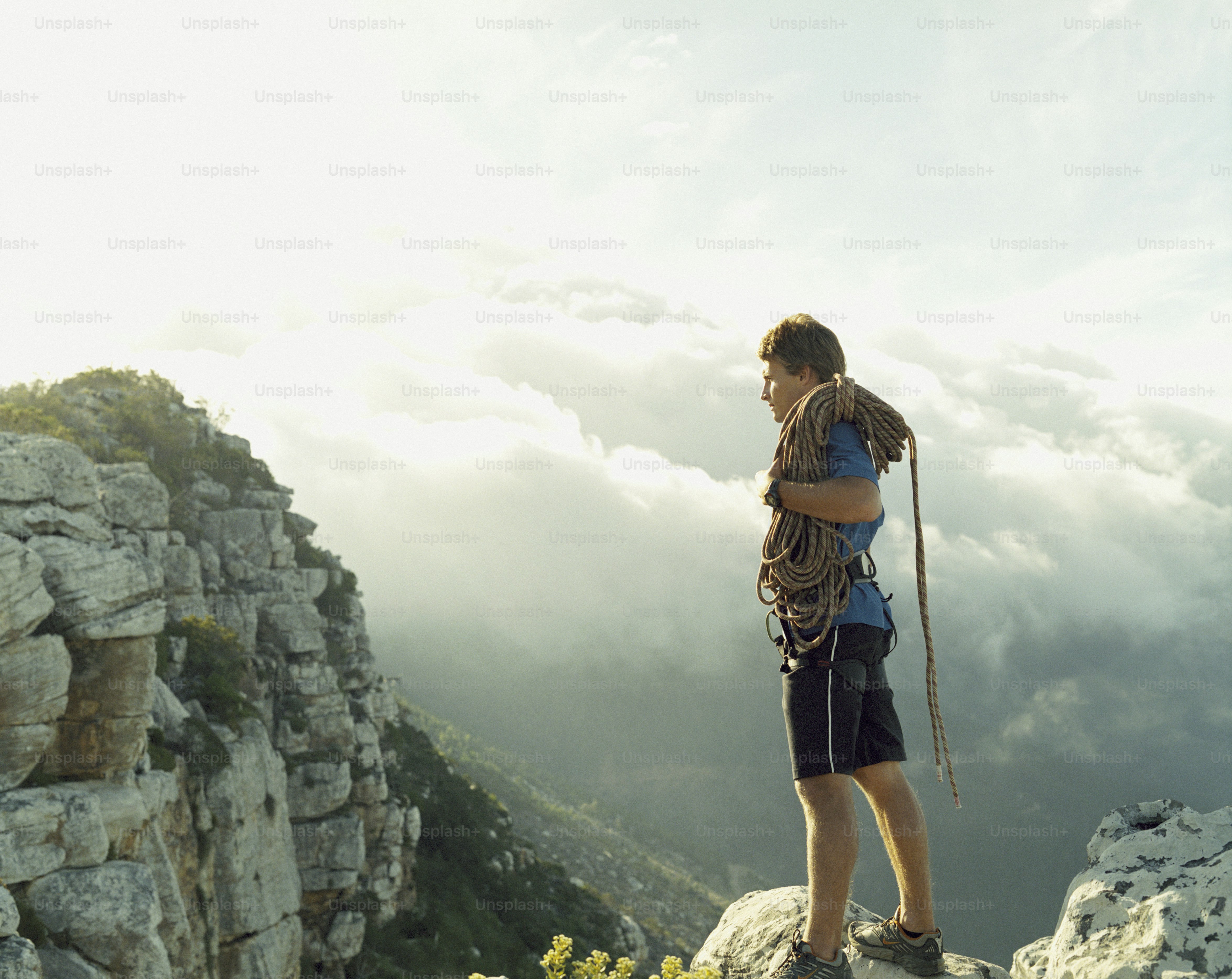 A man standing on top of a mountain with a backpack photo – Young men ...