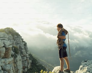 Un uomo in piedi sulla cima di una montagna con uno zaino
