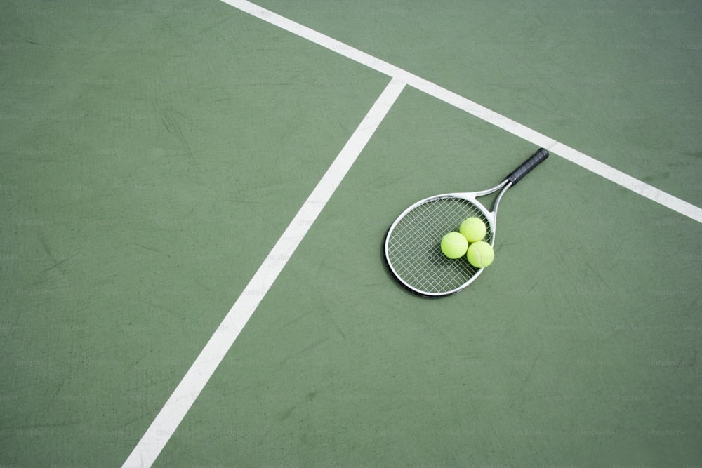 a tennis racket and two tennis balls on a tennis court