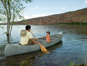 a man and a little girl paddling a canoe