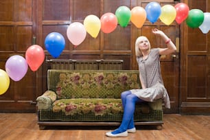 a woman sitting on a couch in front of balloons