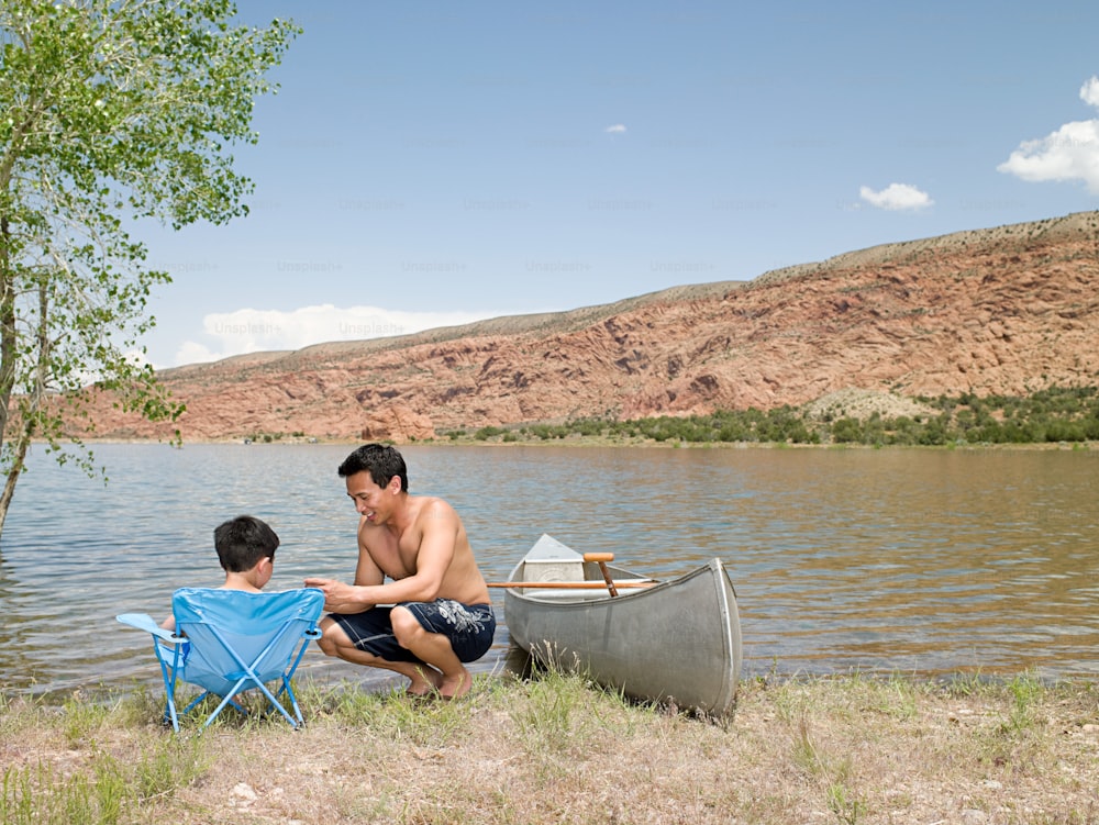 um homem e um menino sentados na margem de um lago