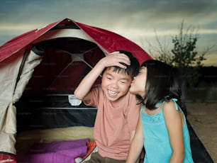 a couple of kids sitting in front of a tent