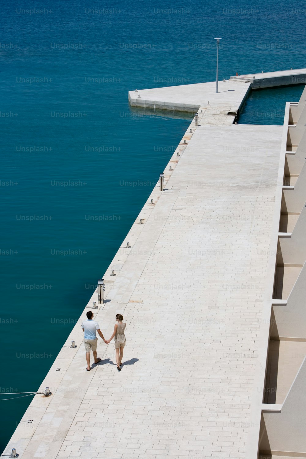 two people walking on a pier holding hands
