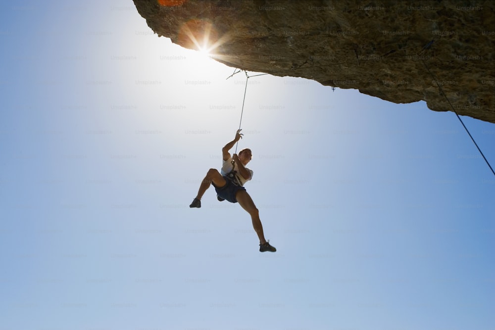 a man hanging from a rope on top of a cliff
