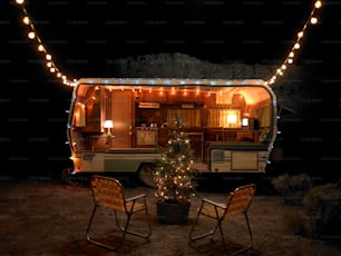 a lit up camper with a christmas tree in the back