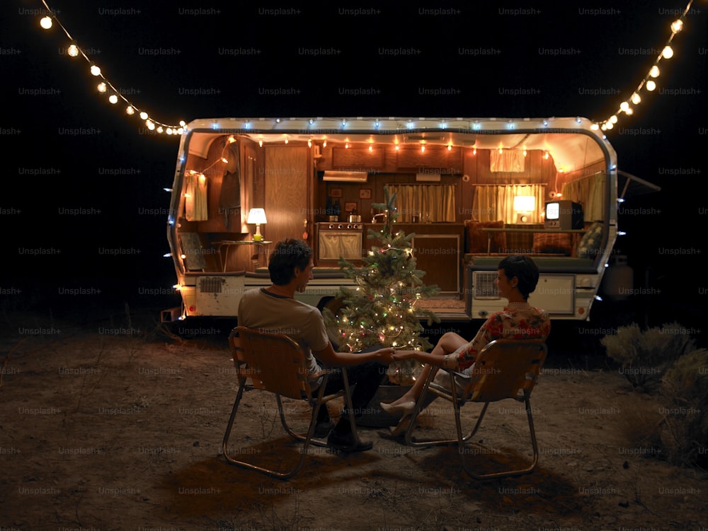 a man and a woman sitting in chairs in front of a trailer