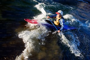 Un hombre montando un kayak encima de un cuerpo de agua