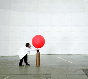um homem segurando um balão vermelho em cima de um poste