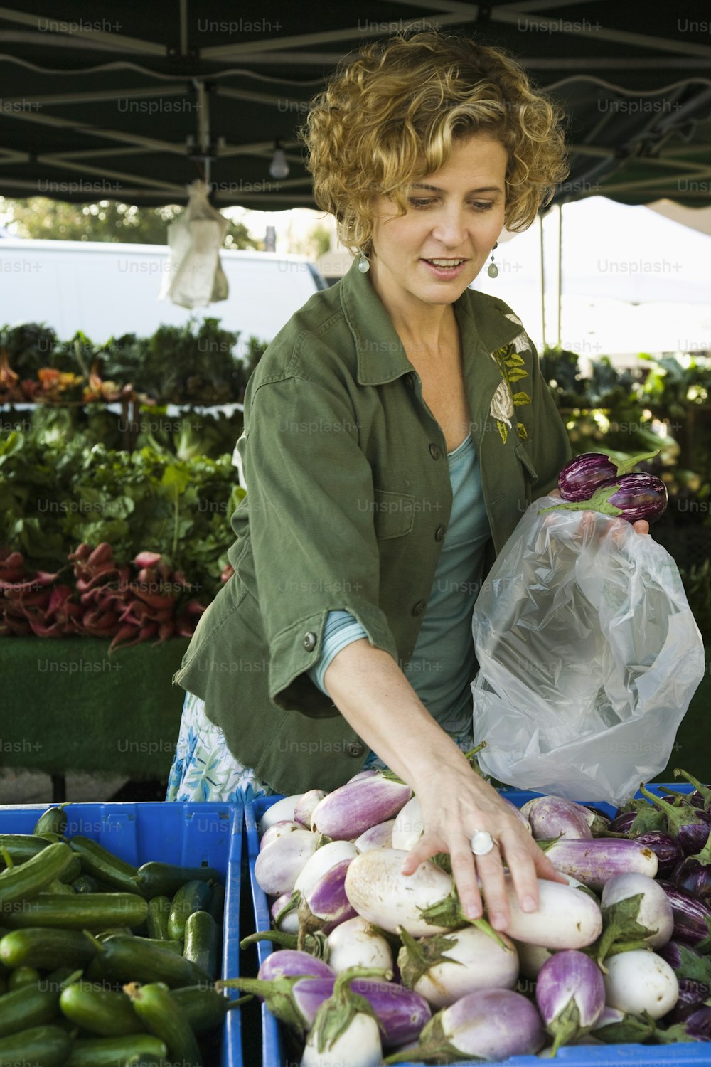 a woman standing in front of a table filled with vegetables