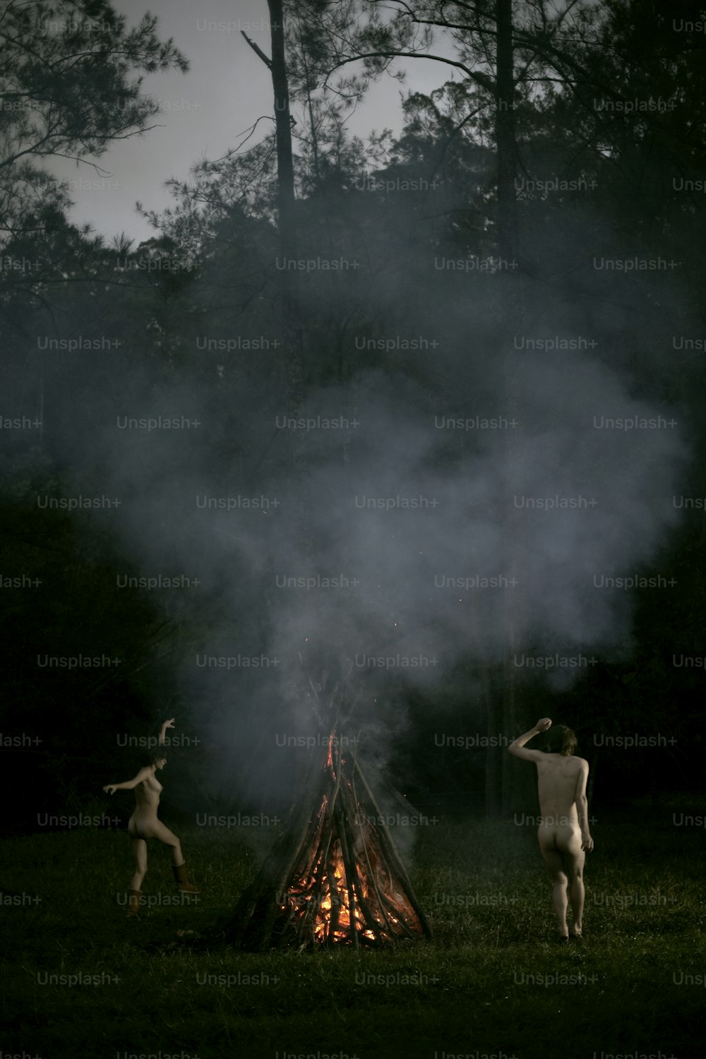 Un couple d’hommes nus debout près d’un feu