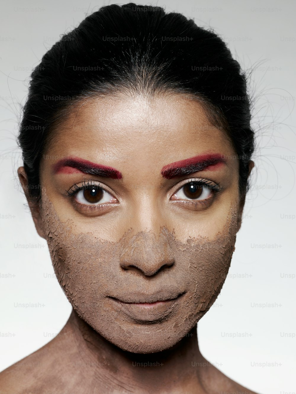 Il volto di una donna è coperto di argilla