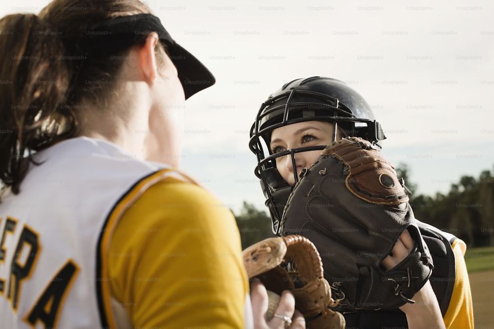 a softball player holding a catchers mitt next to another player