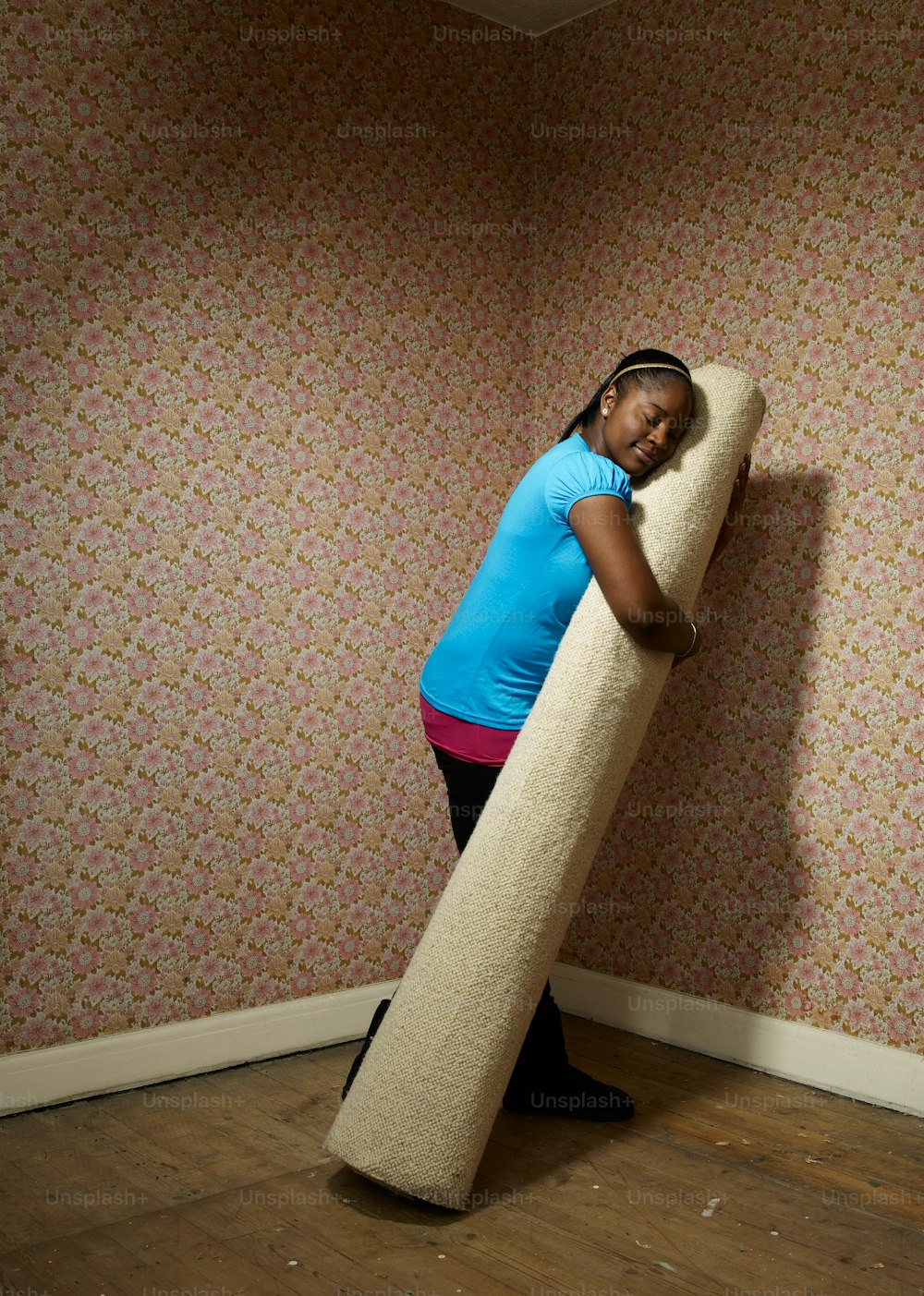 a woman standing in a room holding a large pillow