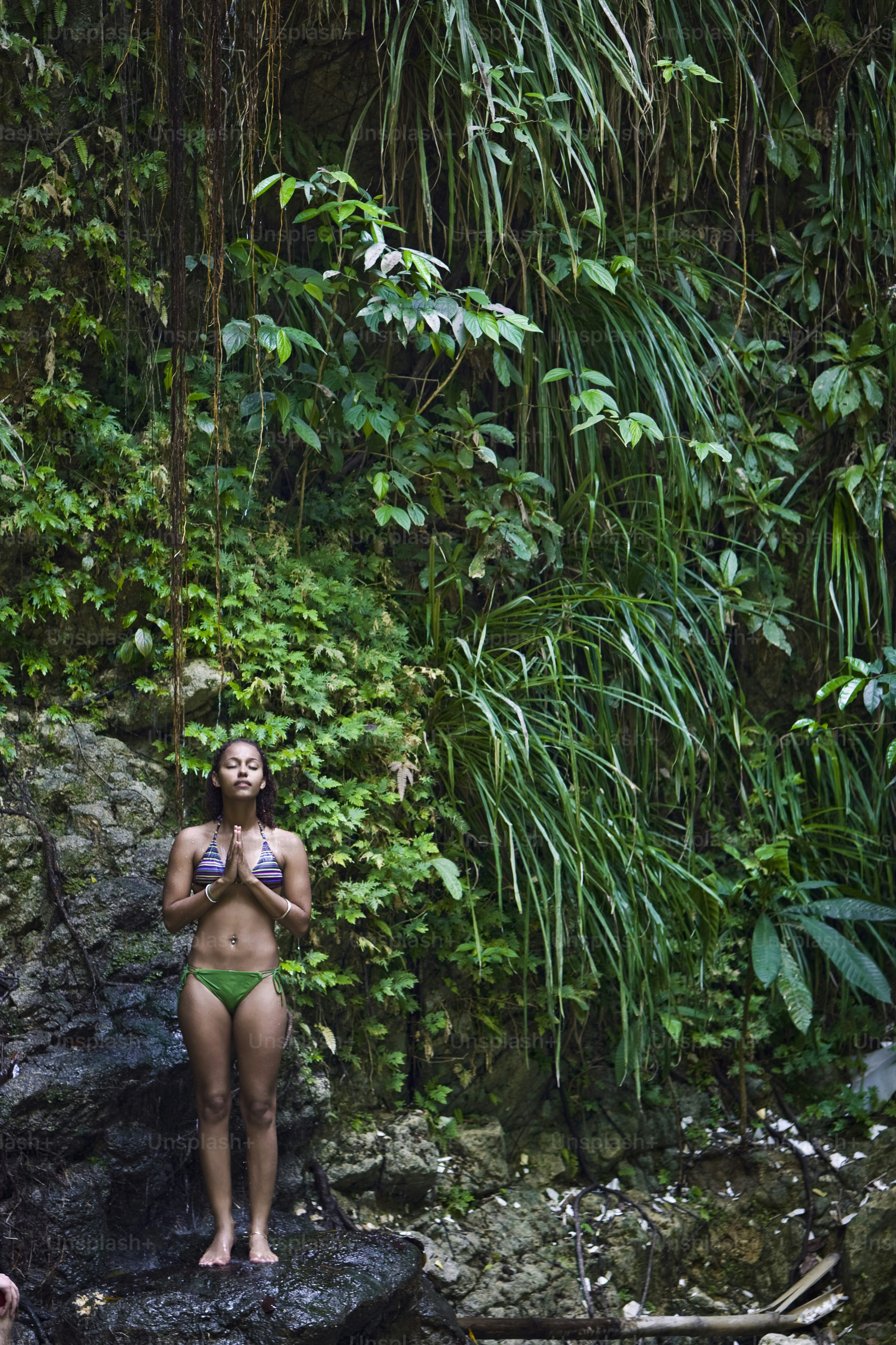 a woman in a bikini standing on a rock