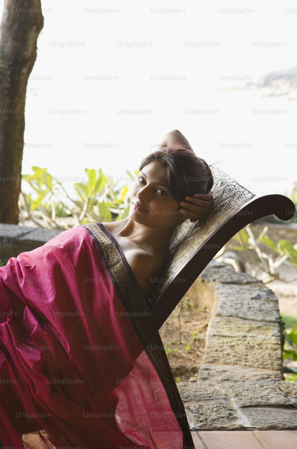 uma mulher em um sari vermelho deitado em uma cadeira de madeira