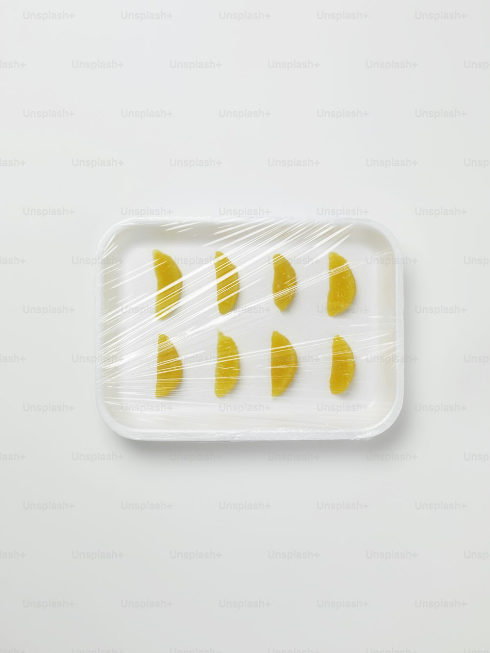 a plastic tray with yellow slices of fruit on it