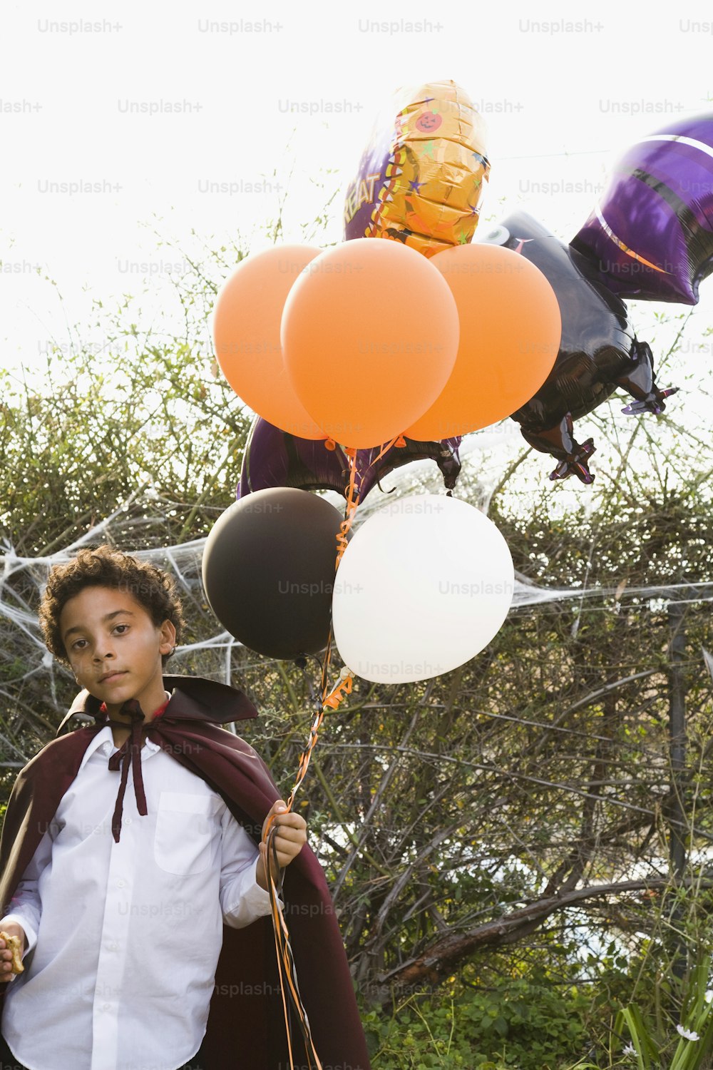 a young boy holding a bunch of balloons