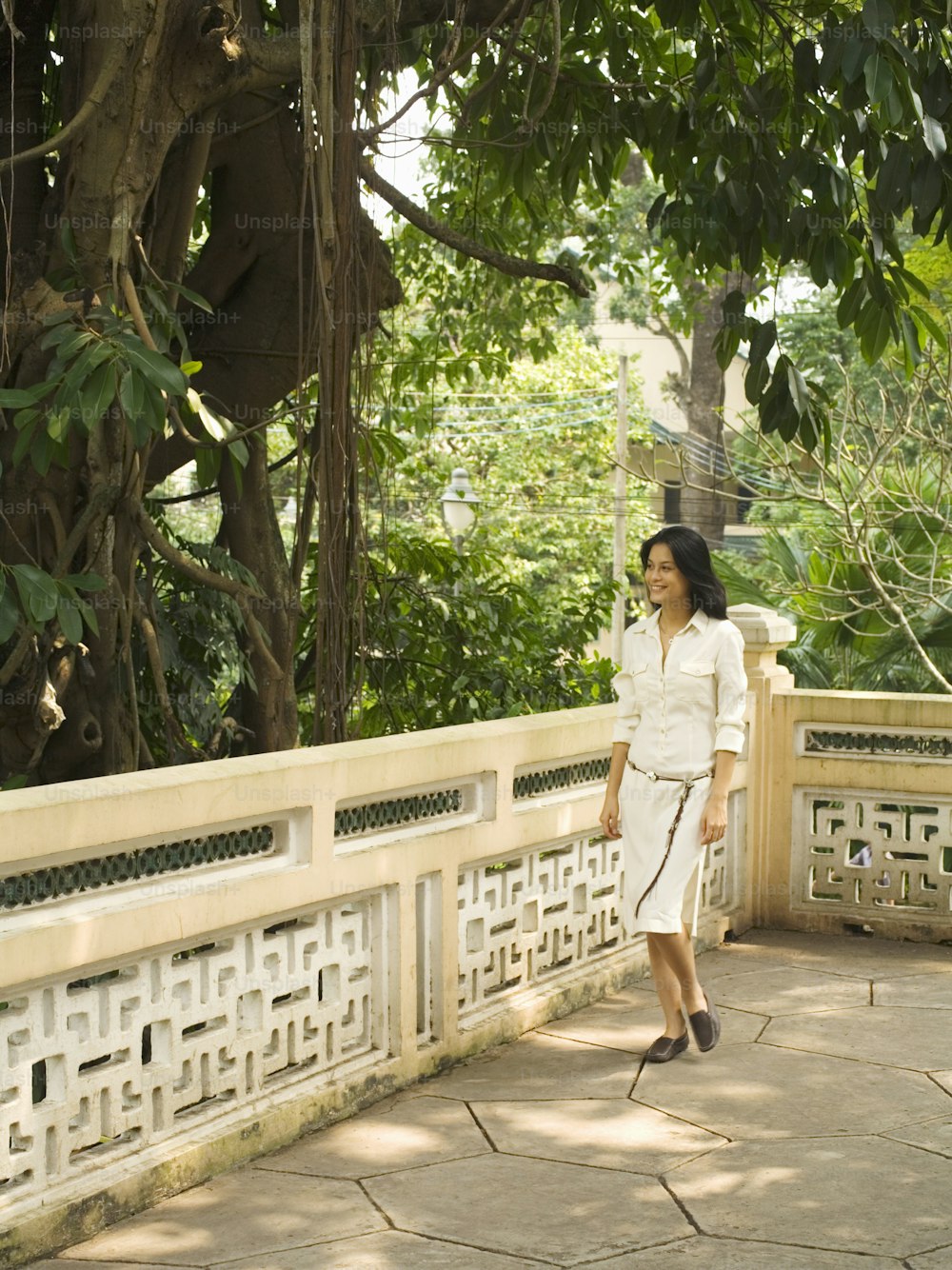 a woman in a white dress walking across a bridge