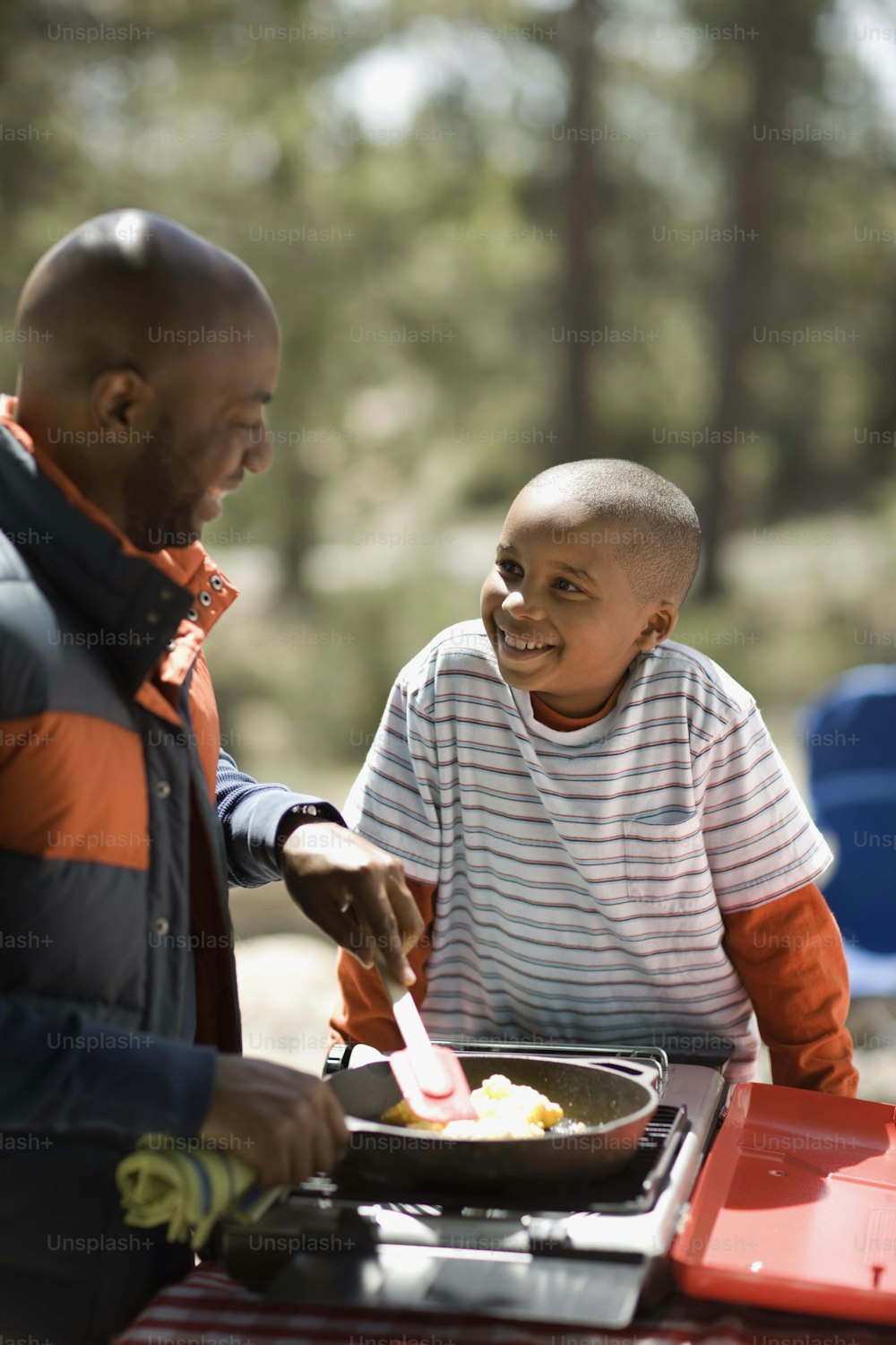 a man and a boy are cooking food on a grill