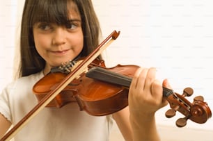 Una niña sosteniendo un violín en sus manos
