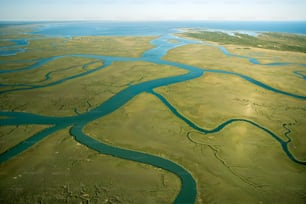 an aerial view of a river running through a lush green field