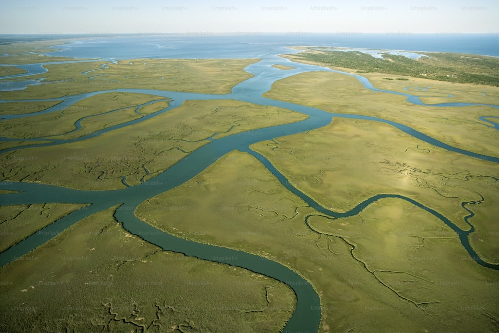 an aerial view of a river running through a lush green field