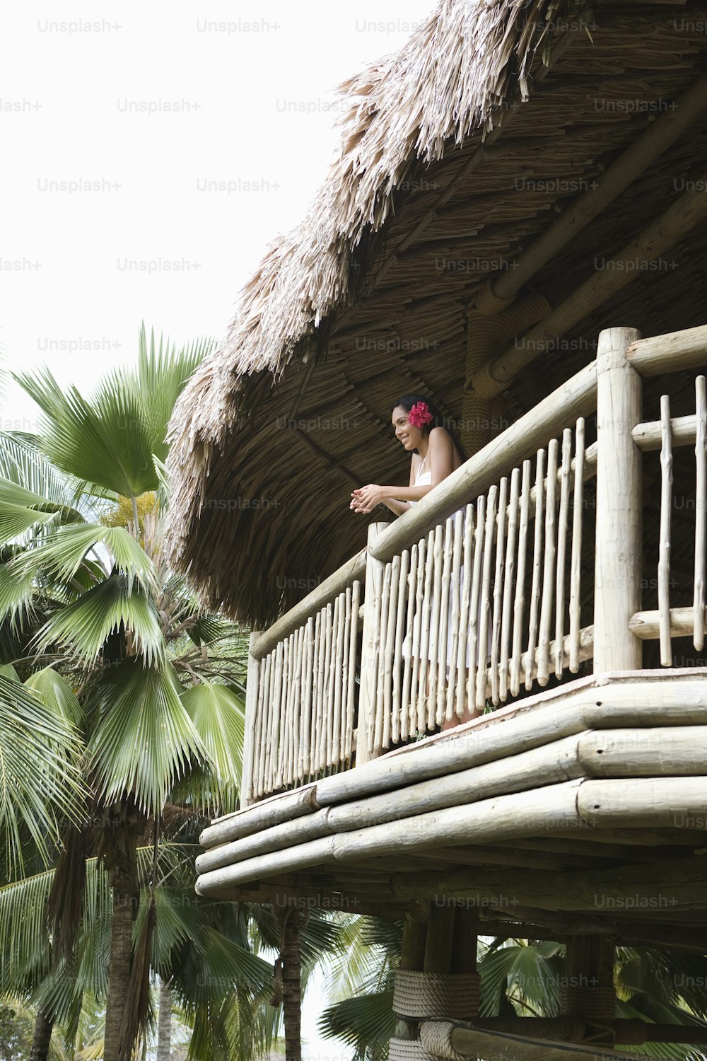 a man standing on a balcony next to a palm tree