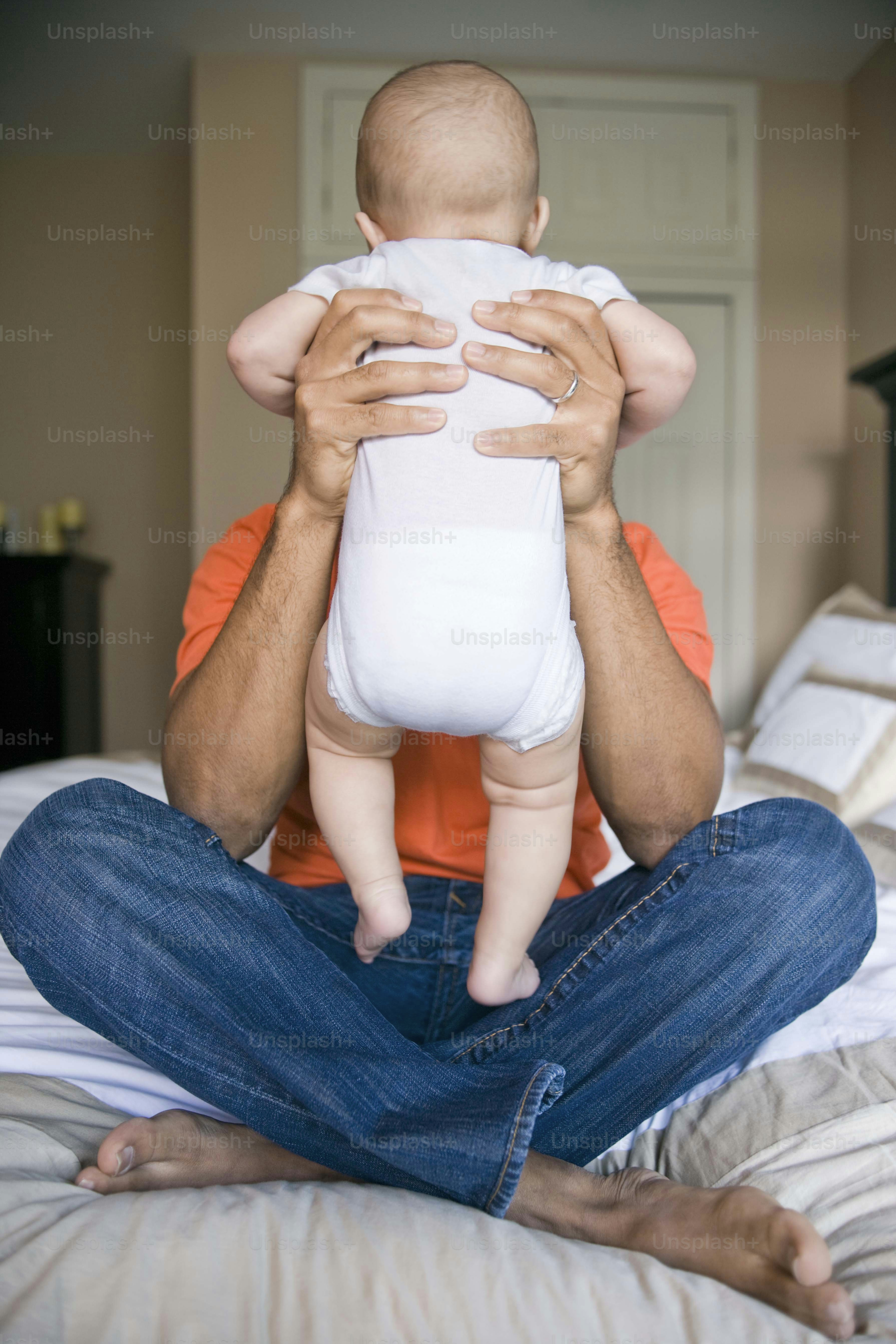 a man sitting on a bed holding a baby