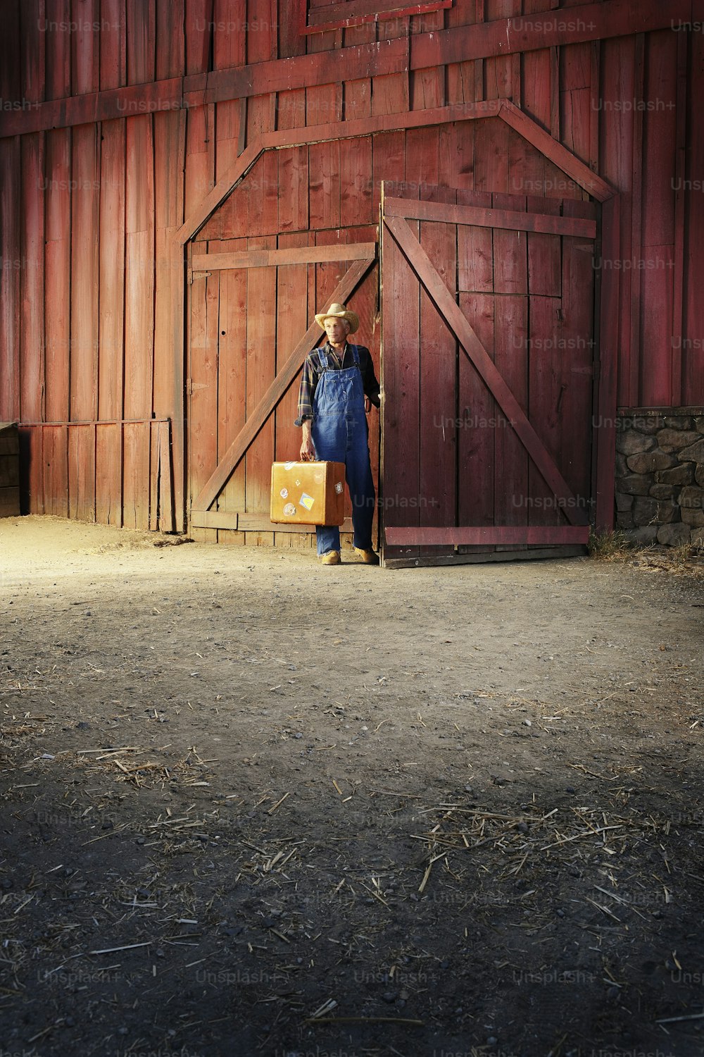 Una mujer parada frente a la puerta de un granero rojo