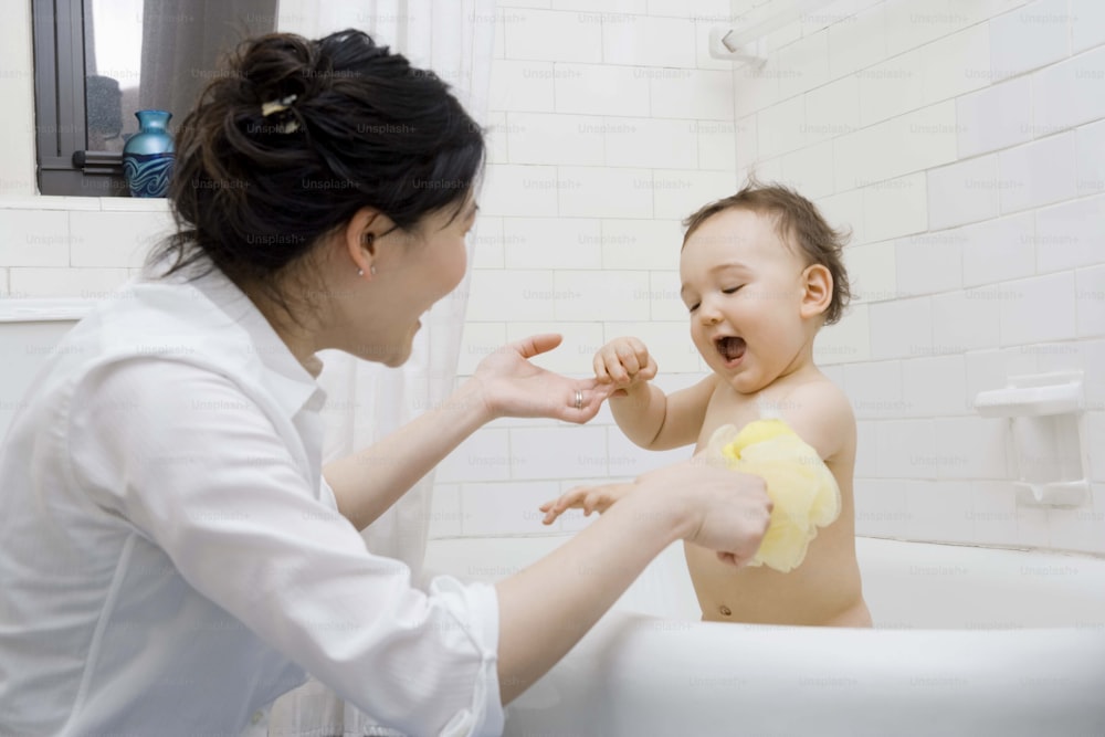 a woman brushing a baby's teeth in a bathtub