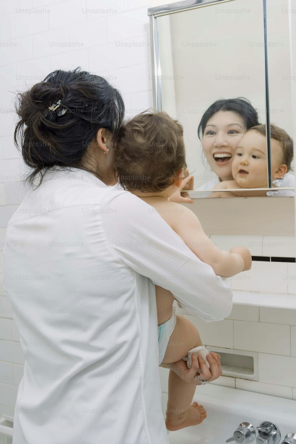 a woman holding a child in front of a mirror