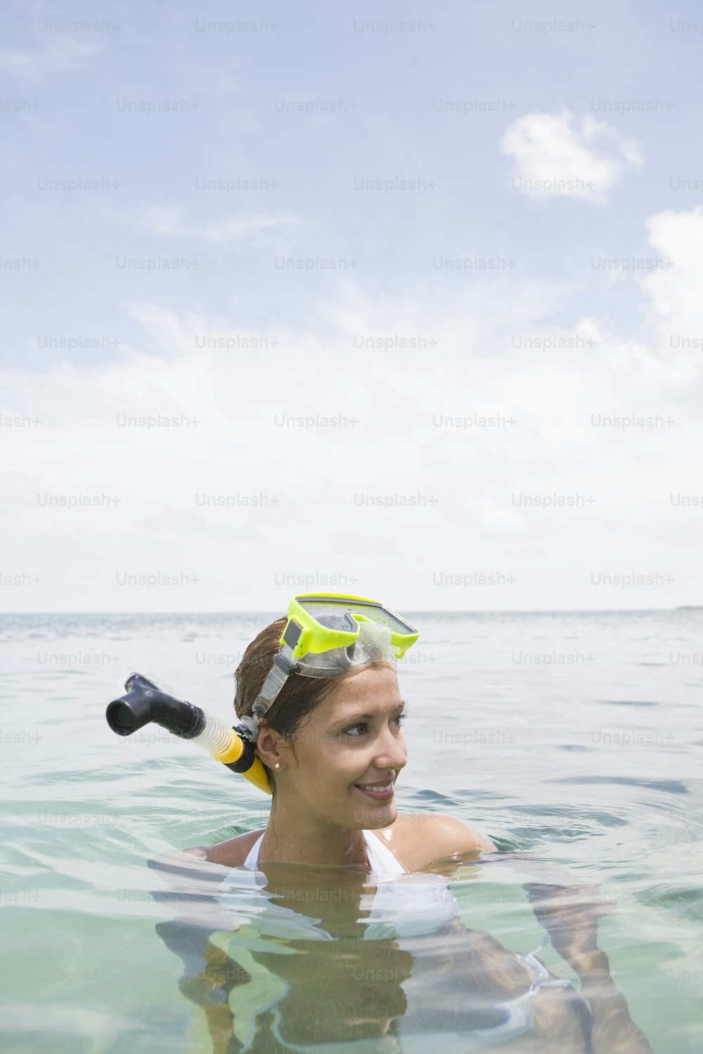 a woman swimming in the ocean with a snorkel on her head