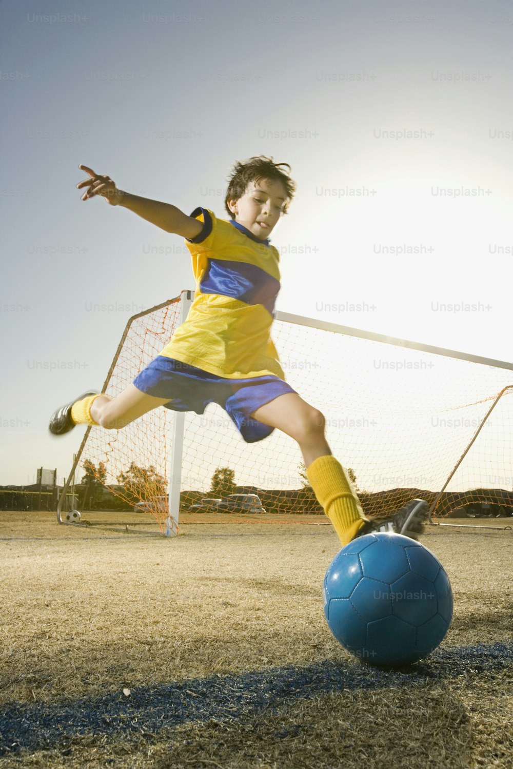 um jovem chutando uma bola de futebol ao redor de um campo