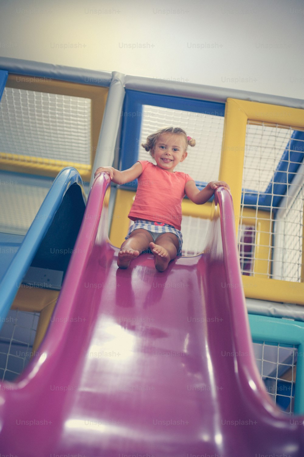 Little girl pin playground. Caucasian girl sliding on toboggan.