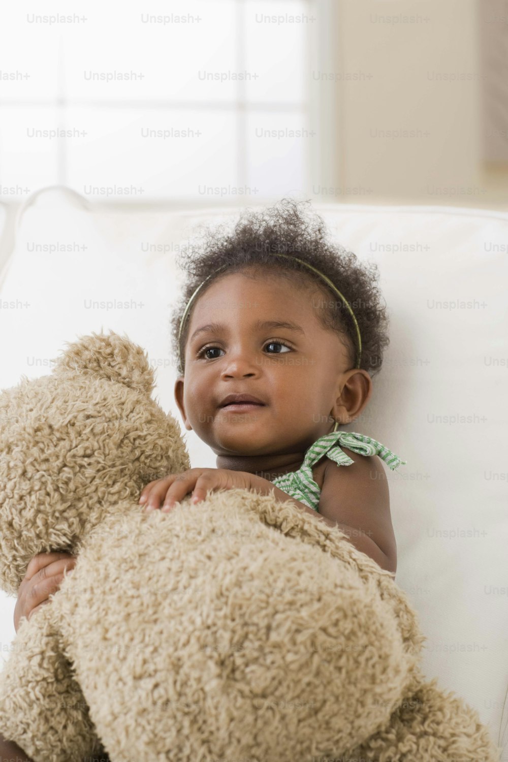a little girl sitting on a couch holding a teddy bear