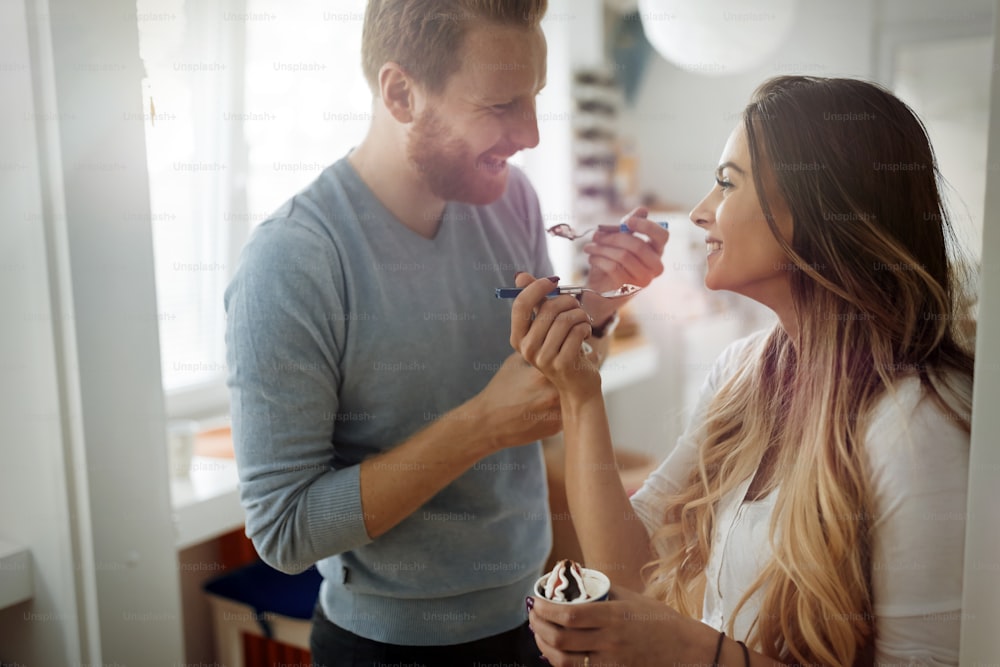 Beautiful couple having fun and laughing at home while eating ice cream
