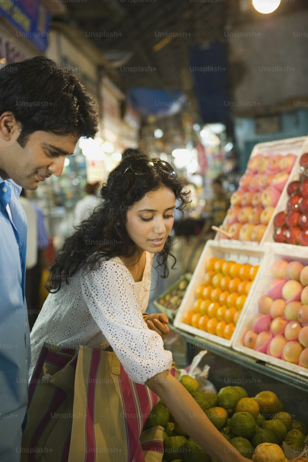 a man and a woman looking at fruit in a market