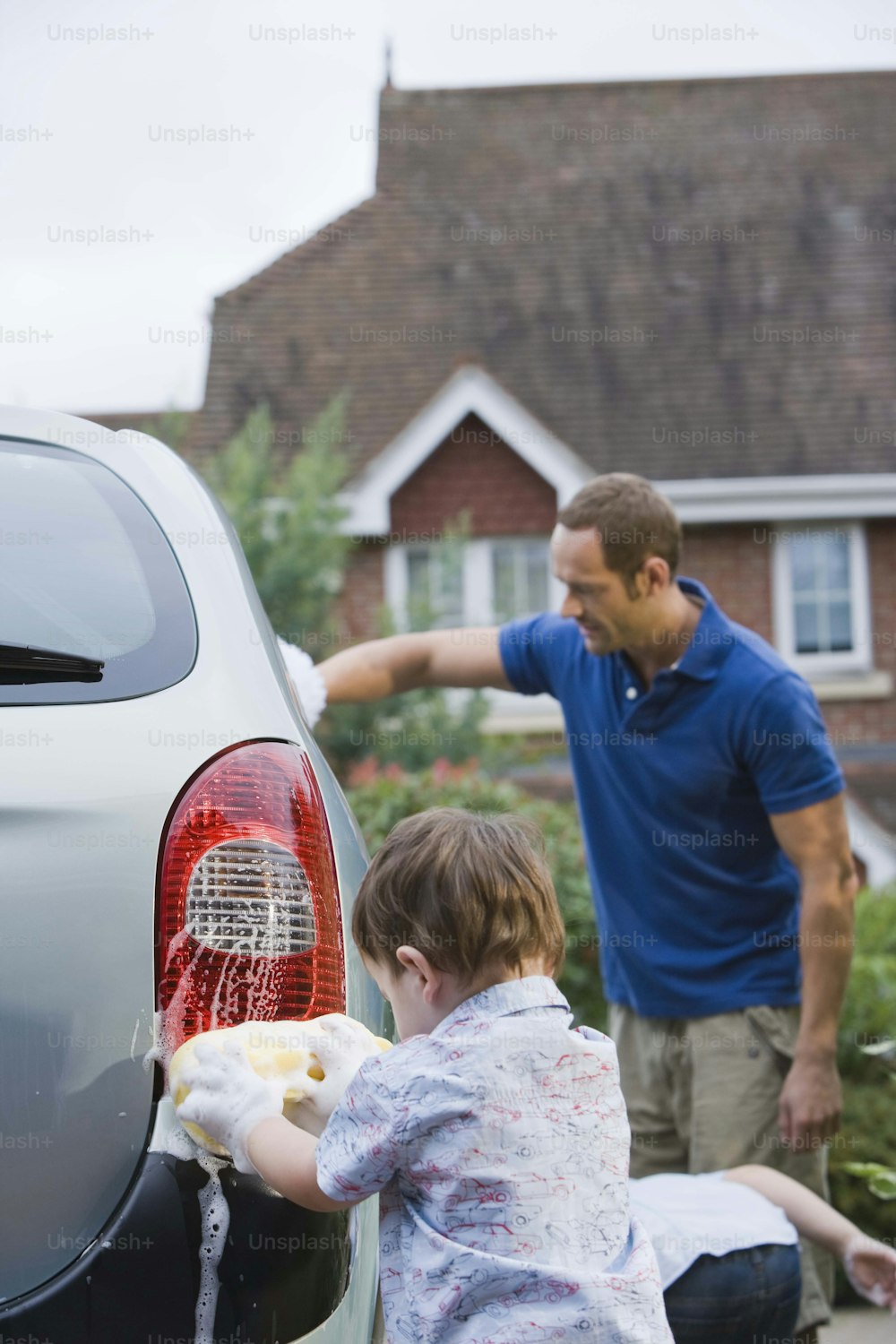 Ein Mann und ein Kind waschen ein Auto