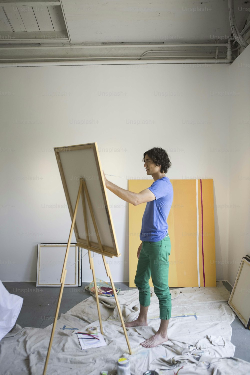 a man standing next to a easel in a room